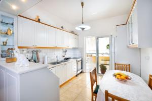 kuchnia z białymi szafkami i stołem z misą owoców w obiekcie Port Apartment w Chanii