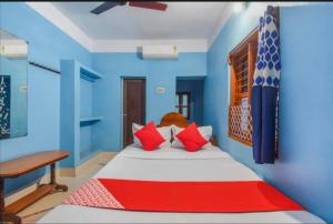 a bedroom with a bed with blue walls and red pillows at Labanya Lodge in Konārka