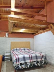 Cama en habitación con techo de madera en El buen descanso en Mar de Ajó