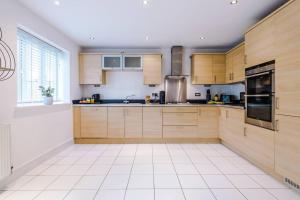 a kitchen with wooden cabinets and a white tile floor at Luxurious Cosy 4BR Home Cheshire in Saughall