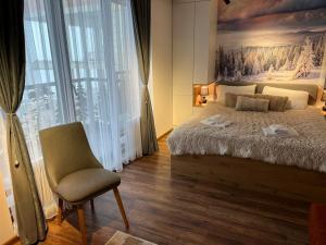 una camera da letto con un letto e una sedia e una grande finestra di Apartmani TIM Ariš Resort a Kopaonik