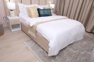una camera da letto con un letto grande con lenzuola e cuscini bianchi di Superb Studio by The Creek view a Dubai