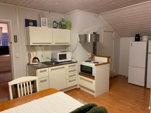 a small kitchen with white cabinets and a white refrigerator at Koskentien kotimajoitus & Luxury Glamping in Jämsä +26 photos