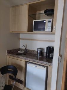 a small kitchen with a counter and a microwave at Lets Idea Hotel Flat Particular in Brasilia