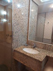 a bathroom with a sink and a shower with a mirror at Lets Idea Hotel Flat Particular in Brasilia