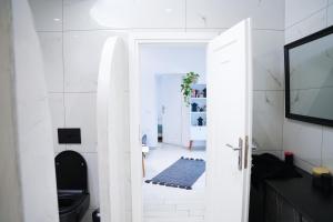 Baño blanco con aseo negro y puerta en SunStone Apartment en Fira
