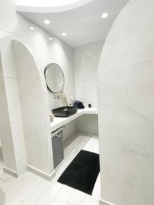 a white bathroom with a sink and a mirror at SunStone Apartment in Fira