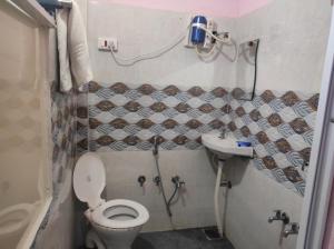 La petite salle de bains est pourvue de toilettes et d'un lavabo. dans l'établissement Vrundavan home stay and Village resort, à Kevadia