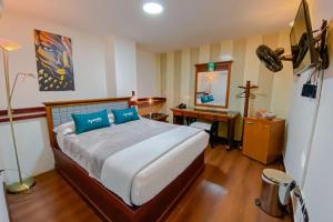 1 dormitorio con cama con almohadas azules y escritorio en Ayenda Imperio Real, en Pereira