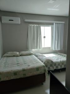 two beds in a bedroom with a window at Casa Capitolio in Capitólio