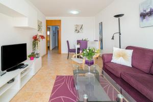 een woonkamer met een paarse bank en een tv bij Alborada Golf 1 3c Spaniahome in L'Alfas del Pi
