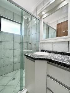y baño con ducha acristalada y lavamanos. en 205 - Apartamento 02 dormitórios apenas 50m praia de Bombas, en Bombinhas