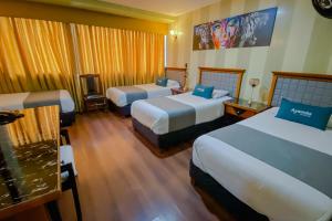um quarto de hotel com três camas com almofadas azuis em Ayenda Imperio Real em Pereira