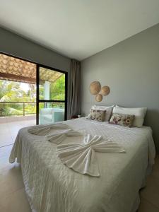 a bedroom with a large white bed with a large window at Bangalôs de Peroba in Maragogi