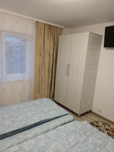 a bedroom with two beds and a cabinet and a window at Apartament lux Lupeni Straja in Lupeni