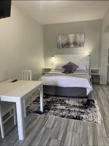 a bedroom with a white bed and a table and a bed sidx sidx at 22 on Mirabel in Kempton Park