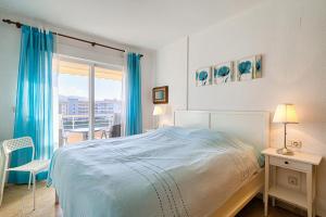 een slaapkamer met een bed en een raam met blauwe gordijnen bij Alborada Golf 1 3c Spaniahome in L'Alfas del Pi