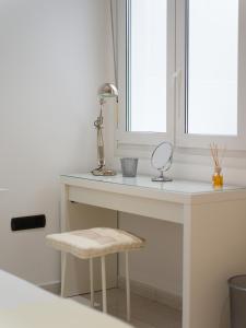 een wit bureau met een spiegel en een kruk bij HomeForGuest Modern Apartment in the centre of Puerto del Rosario in Puerto del Rosario