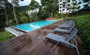 a row of chairs sitting on a deck next to a swimming pool at Genting View Resort GVR Kempas in Genting Highlands