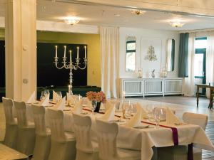 a conference room with a long table with white chairs at Hotel Garni Zum Dorfbrunnen in Bornheim