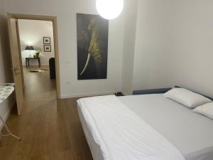 a bedroom with a white bed and a hallway with an elephant painting at MB luxury apartments in Tirana
