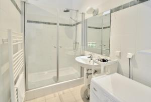 a white bathroom with a shower and a sink at Beautiful Flat Next to Karlskirche in Vienna +20 photos