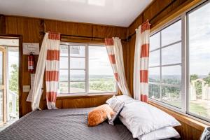 - une chambre avec un lit et de grandes fenêtres dans l'établissement Gavra Cabana at Bella Vue Estate, à Georgeville