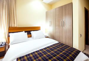 a bedroom with a bed and a wooden cabinet at Rushmore - Standard Room in Lagos