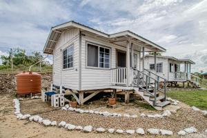 uma pequena casa com um grande alpendre e escadas em Jehane Cabana at Bella Vue Estate em Georgeville