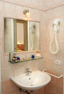 La salle de bains est pourvue d'un lavabo et d'un miroir. dans l'établissement Residence Corallo, à Caorle