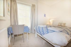 a bedroom with a bed and a desk and a window at Beautiful Aberdovey Seafront Apartment 2 in Aberdyfi +15 photos