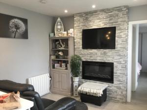 a living room with a stone fireplace with a flat screen tv at Leafy Lytham central Lovely ground floor 1 bedroom apartment with private garden In Lytham dog friendly in Lytham St Annes