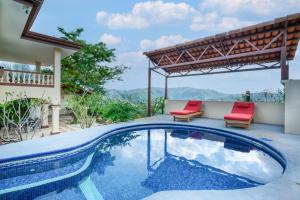 a swimming pool with two red chairs next to a house at Casa Gerónimo in Playa Hermosa