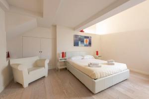 een witte slaapkamer met een bed en een stoel bij Le Grazie Luxury Apartment in Florence