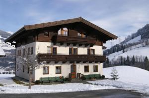 un grand bâtiment avec bancs dans la neige dans l'établissement Vordergugg, à Mittersill