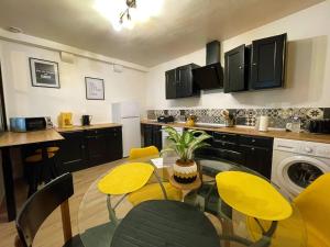 a kitchen with a glass table and yellow chairs at CAPORIZON-La Verrière-Clos de Chambord-à coté du Chateau in Saint-Claude-de-Diray