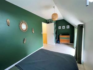 ein Schlafzimmer mit grünen Wänden, einem Bett und einem Spiegel in der Unterkunft CAPORIZON-La Verrière-Clos de Chambord-à coté du Chateau in Saint-Claude-de-Diray