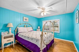 um quarto azul com uma cama e uma ventoinha de tecto em Fanci's Hideout em Atlantic Beach