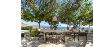 a table and chairs under trees on the beach at Morfia Villas in Piso Livadi