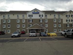 un gran edificio con coches estacionados en un estacionamiento en Days Inn & Suites by Wyndham Rochester South en Rochester