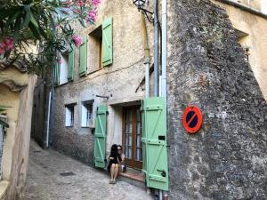 una mujer sentada en la puerta de un edificio en Traditional Provencal Stone House, en Entrecasteaux