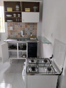a white kitchen with a stove and a sink at Apartamento cercado por natureza e diversão in Maceió