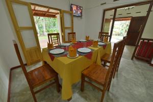 a dining room with a yellow table and chairs at Venus Resorts in Danwilana