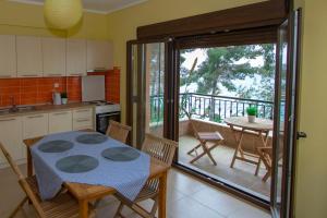 a kitchen with a table and chairs and a balcony at Beachfront Villa Possidi by Halkidiki Villas in Possidi