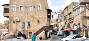 a brick building with a car parked next to a street at Mina Akko sea view in ‘Akko