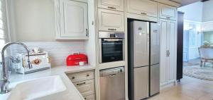 a kitchen with white cabinets and a stainless steel refrigerator at Mina Akko sea view in Acre