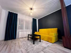 a living room with a yellow couch and a table at BB Apartaments Dream Village in Iaşi