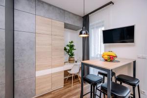 Habitación con mesa con taburetes y TV. en Amade Apartments en Győr