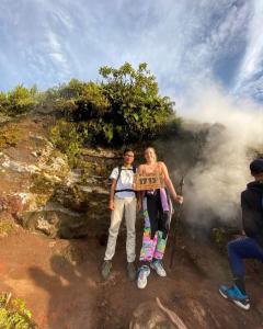 two people holding up a sign on a mountain at Batur lake view in Kintamani
