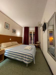 ein Schlafzimmer mit einem Bett mit einer blau-weißen gestreiften Decke in der Unterkunft P&R hostals Maria Rosa in Tossa de Mar